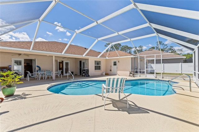 view of pool featuring glass enclosure, a patio, a fenced in pool, fence, and ceiling fan