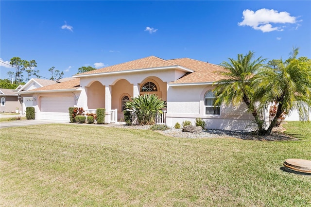 mediterranean / spanish home with a front lawn, an attached garage, and stucco siding