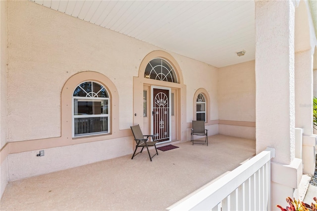 doorway to property featuring stucco siding and a porch