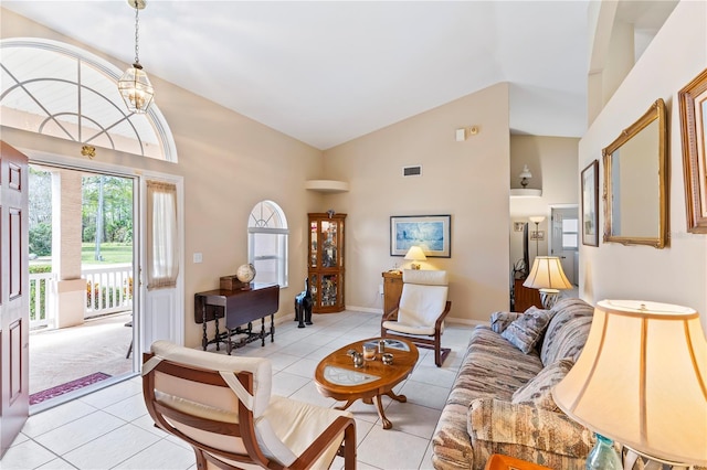 living area with light tile patterned floors, visible vents, high vaulted ceiling, and baseboards