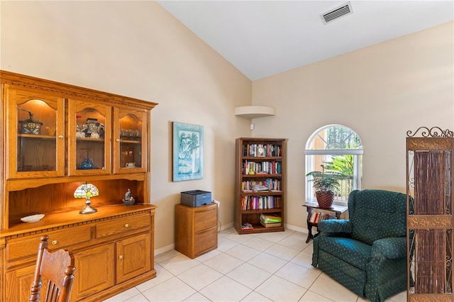 sitting room with light tile patterned flooring, visible vents, baseboards, and lofted ceiling