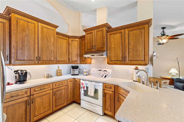 kitchen with under cabinet range hood, brown cabinetry, electric stove, and a sink