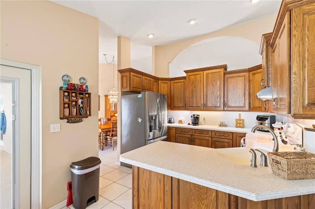 kitchen featuring light tile patterned floors, stainless steel fridge, a peninsula, and light countertops