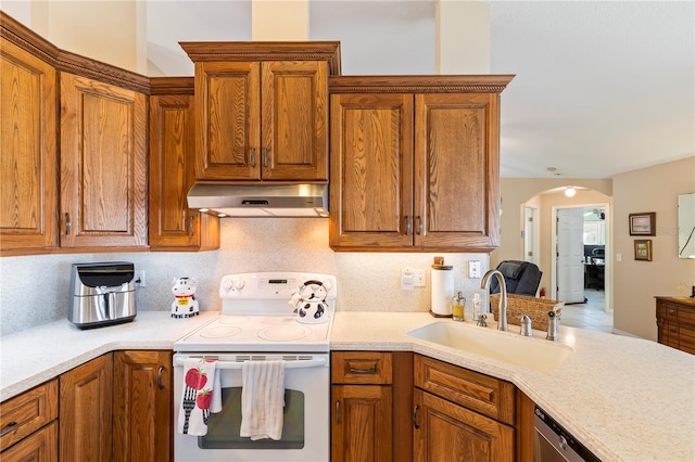 kitchen with under cabinet range hood, brown cabinetry, white electric range oven, and a sink