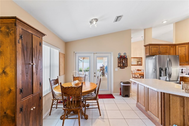 dining space with visible vents, baseboards, french doors, light tile patterned floors, and lofted ceiling