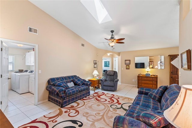 living area featuring visible vents, vaulted ceiling with skylight, separate washer and dryer, light tile patterned floors, and ceiling fan