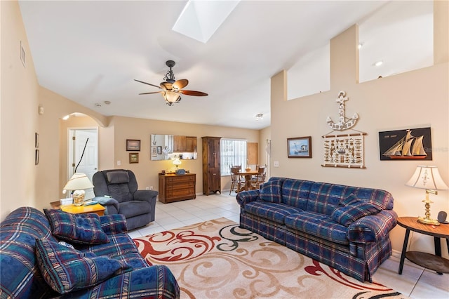 living room with arched walkways, light tile patterned floors, a skylight, and ceiling fan