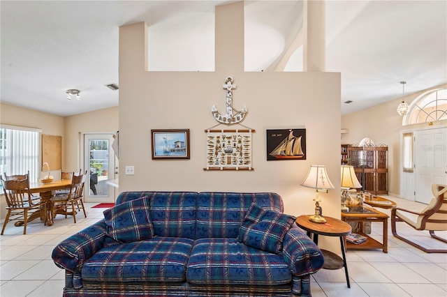 living area with tile patterned flooring, vaulted ceiling, and visible vents