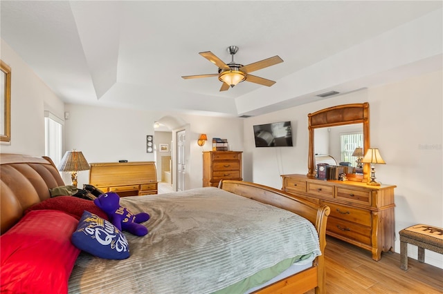 bedroom featuring visible vents, a raised ceiling, a ceiling fan, and wood finished floors