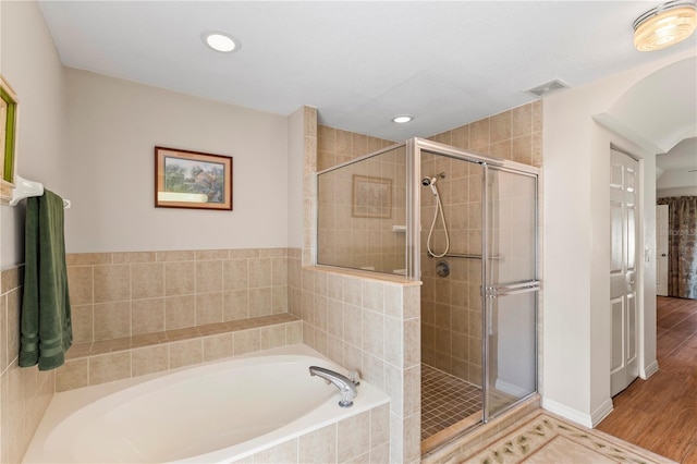 full bathroom featuring visible vents, wood finished floors, a bath, and a shower stall