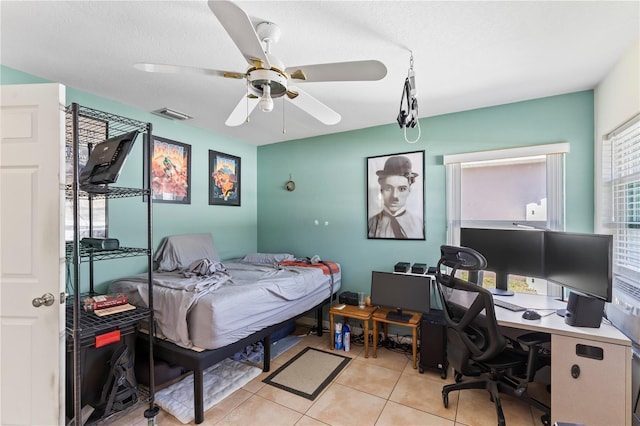 bedroom featuring a textured ceiling, light tile patterned floors, visible vents, and ceiling fan