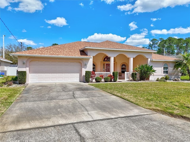 view of front of home with an attached garage, a front yard, covered porch, stucco siding, and driveway