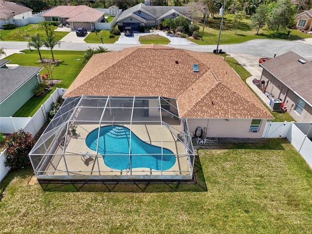 view of swimming pool featuring a lawn, a fenced backyard, glass enclosure, a residential view, and a fenced in pool