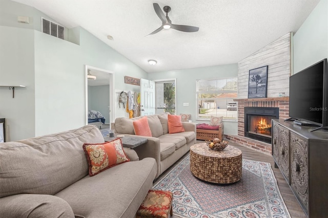 living area with a fireplace, lofted ceiling, wood finished floors, and visible vents