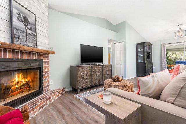 living room featuring vaulted ceiling, a brick fireplace, wood finished floors, and baseboards