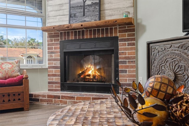 details featuring a brick fireplace and wood finished floors