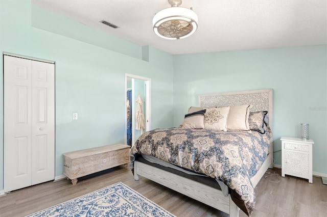 bedroom featuring a closet, visible vents, baseboards, and wood finished floors