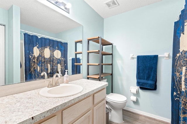 full bath featuring wood finished floors, baseboards, visible vents, a textured ceiling, and toilet