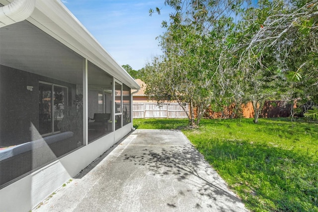 view of yard featuring a patio, fence, and a sunroom