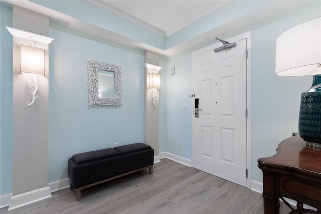 foyer featuring wood finished floors, baseboards, and ornamental molding