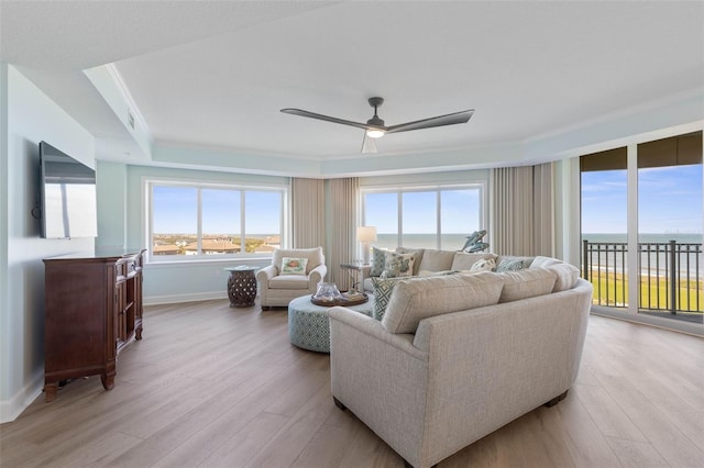 living room featuring light wood-style flooring, baseboards, ceiling fan, and ornamental molding