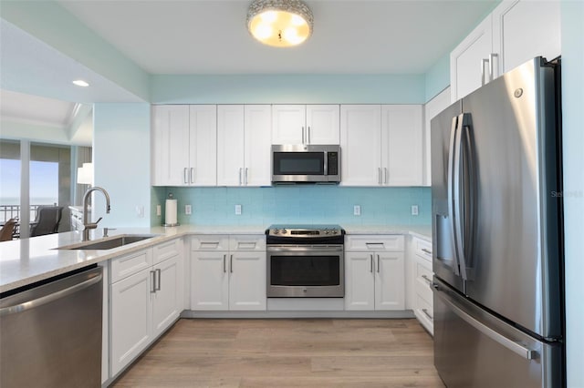 kitchen featuring appliances with stainless steel finishes, white cabinetry, and a sink