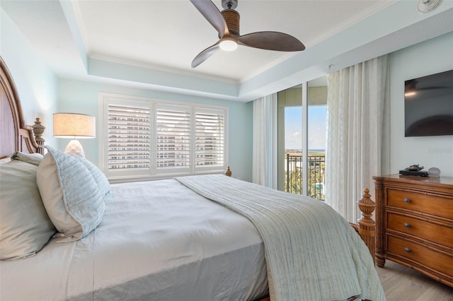 bedroom featuring access to exterior, a tray ceiling, and ornamental molding