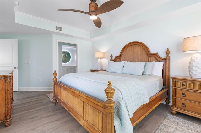 bedroom with visible vents, a raised ceiling, baseboards, and light wood finished floors