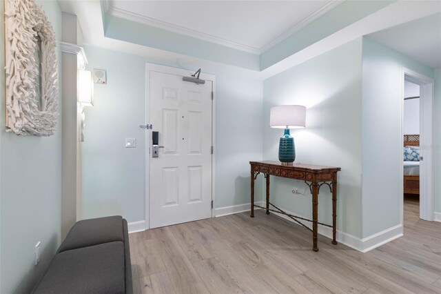 foyer featuring baseboards, light wood-style floors, and ornamental molding