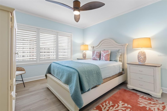 bedroom with crown molding, a ceiling fan, baseboards, and light wood finished floors