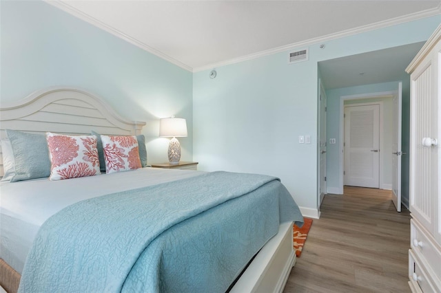 bedroom with crown molding, light wood-style flooring, baseboards, and visible vents