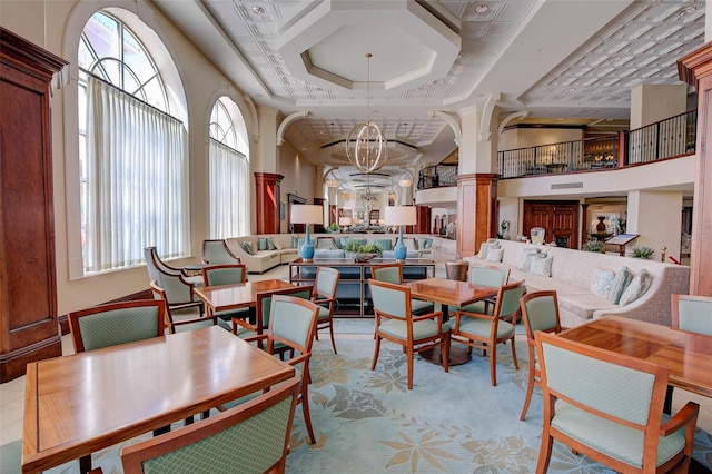 dining space with a notable chandelier, a towering ceiling, and decorative columns