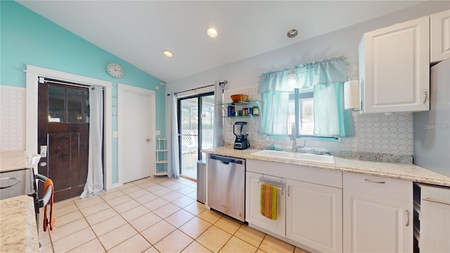 kitchen featuring dishwasher, lofted ceiling, light tile patterned floors, white cabinetry, and a sink