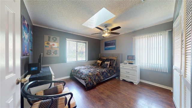 bedroom with a textured ceiling, a skylight, a ceiling fan, and wood finished floors