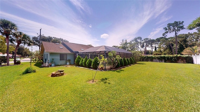 view of yard with a fire pit, a lanai, and fence