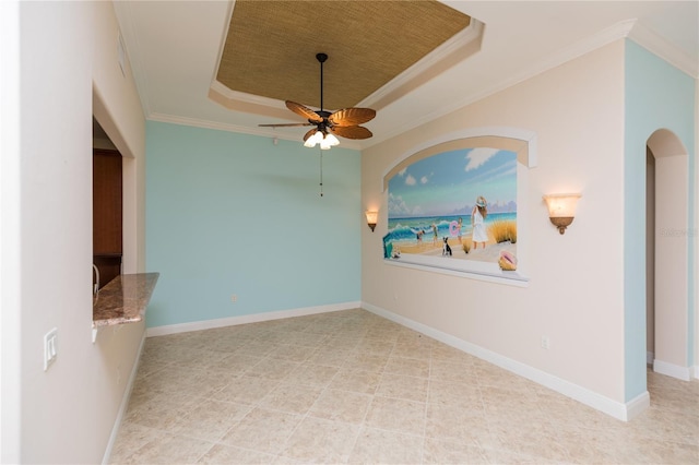 spare room with a tray ceiling, baseboards, ceiling fan, and crown molding