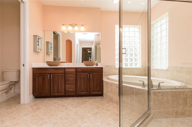 full bathroom featuring tile patterned flooring, toilet, a garden tub, double vanity, and a sink