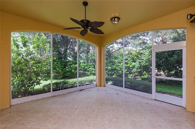 unfurnished sunroom featuring a wealth of natural light, a ceiling fan, and vaulted ceiling