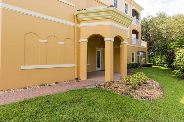 exterior space with stucco siding and a lawn