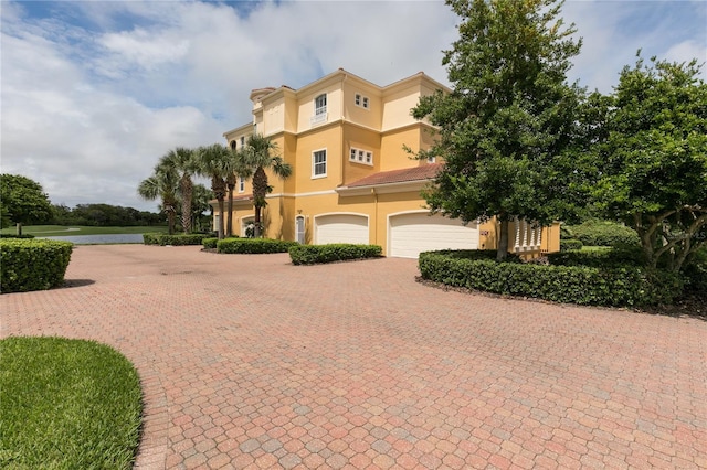 view of front facade with decorative driveway, an attached garage, and stucco siding