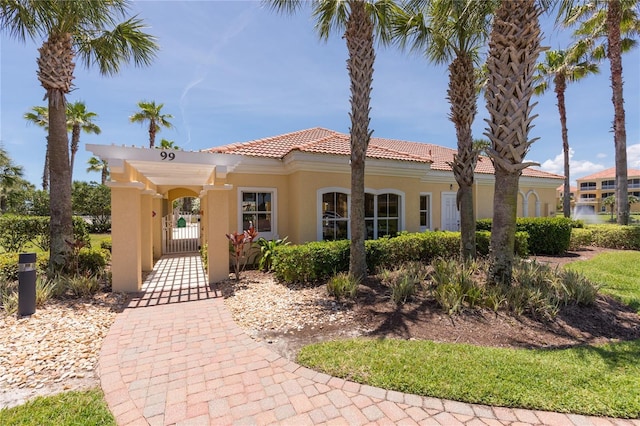 mediterranean / spanish-style home featuring stucco siding, a tiled roof, and a gate