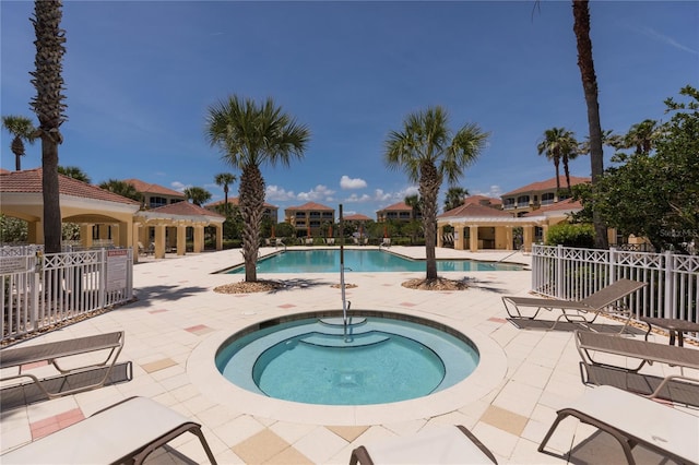 community pool featuring a patio, a hot tub, and fence