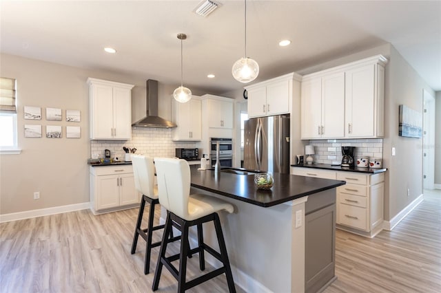 kitchen featuring dark countertops, wall chimney range hood, visible vents, and appliances with stainless steel finishes