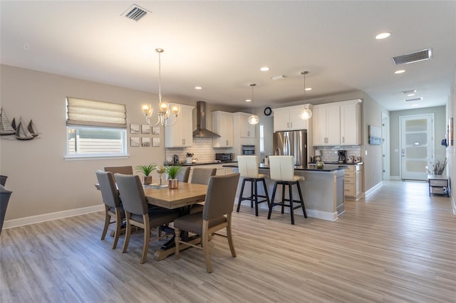 dining space with visible vents, baseboards, and light wood-style flooring