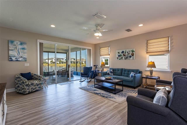 living room featuring a wealth of natural light, visible vents, and light wood finished floors