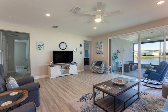 living room with light wood finished floors, visible vents, a ceiling fan, and baseboards