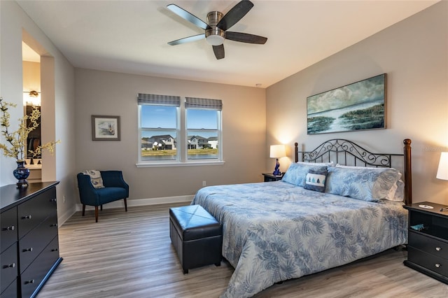 bedroom featuring ceiling fan, baseboards, and light wood-style flooring