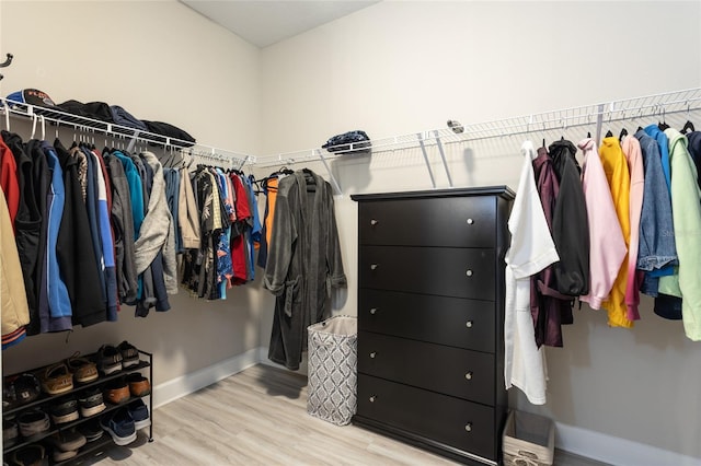 walk in closet with light wood-style flooring