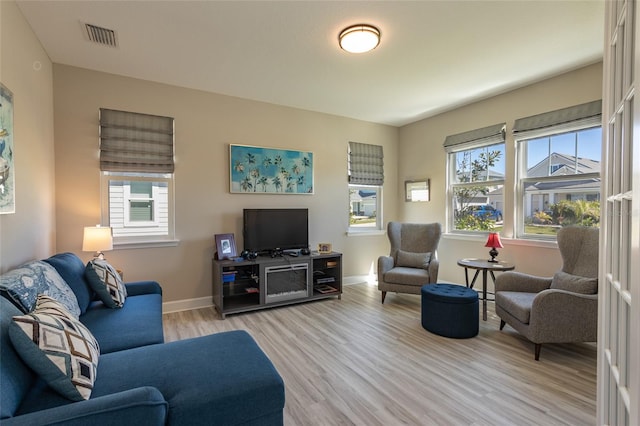 living area featuring visible vents, baseboards, and light wood finished floors