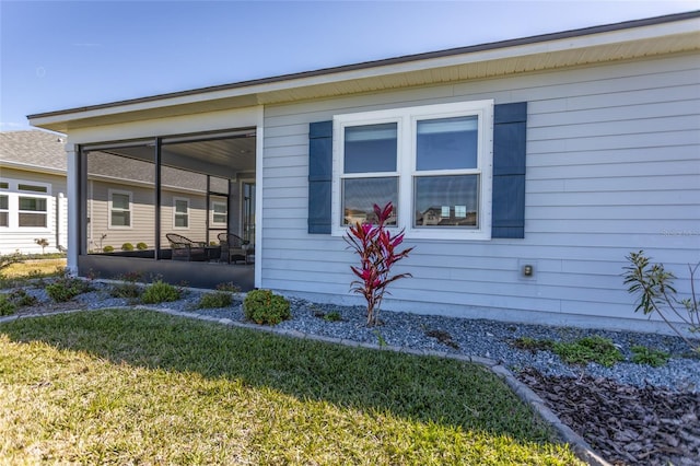 view of side of home with a lawn and a sunroom